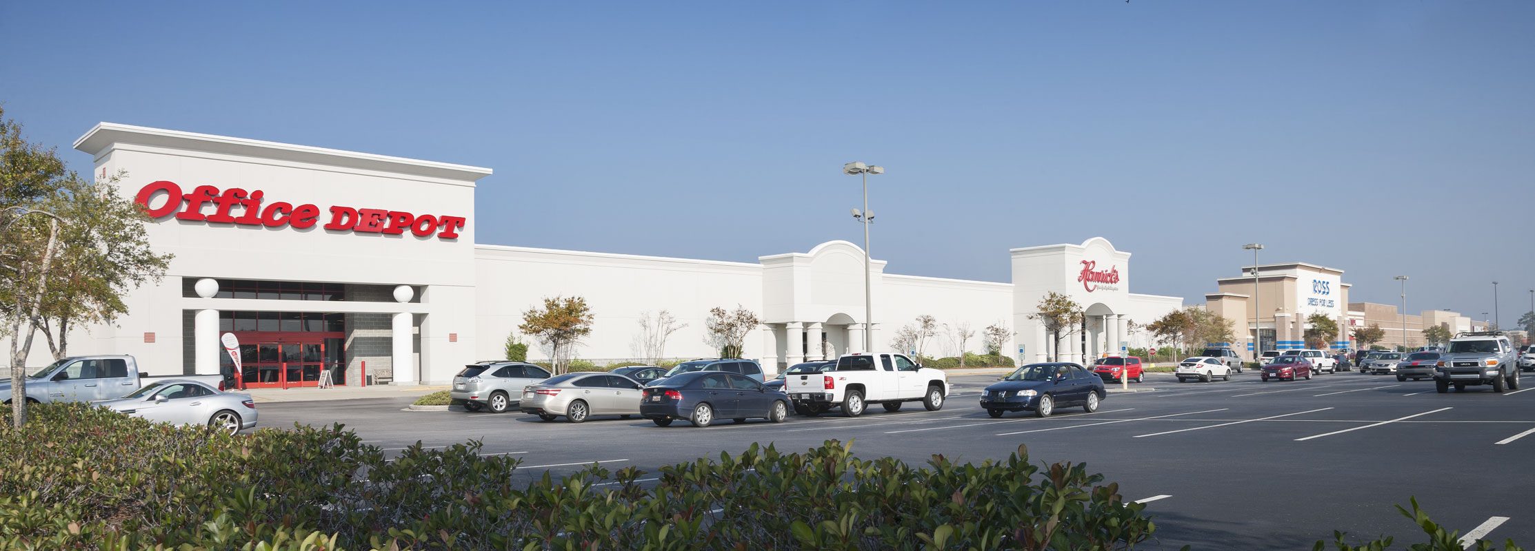 Cars in plaza lot; Office Depot, Petco, Best Buy visible.