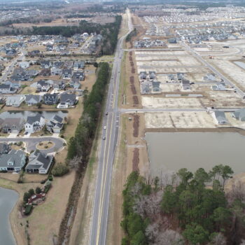 Aerial view: houses on one side, new construction opposite.
