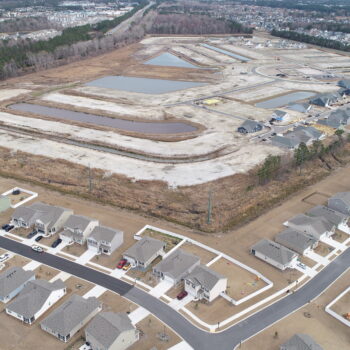 Suburban homes foreground, new housing development under construction background.
