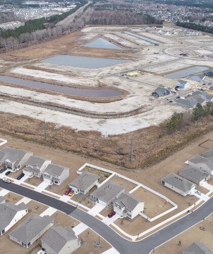 Suburban homes foreground, new housing development under construction background.