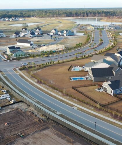 Aerial view of suburban homes, roads, construction, and pond.