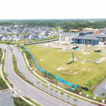 Aerial view: suburb with curved roads, houses, construction, canal.
