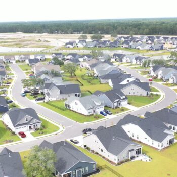 Aerial view of suburban homes, curved streets, lawns, and ponds.