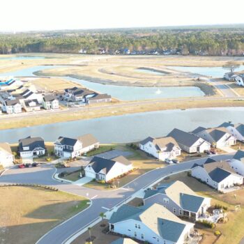 Aerial view of suburban homes, ponds, and distant green spaces.