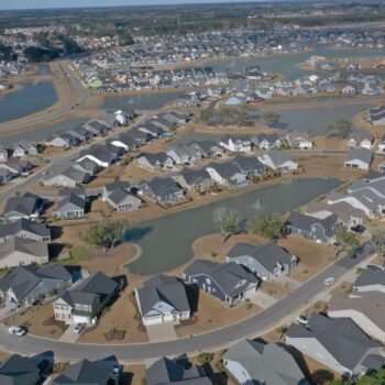 Aerial view of houses around ponds and winding roads.
