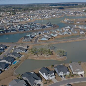 Suburban homes circle ponds along winding streets, aerial view.