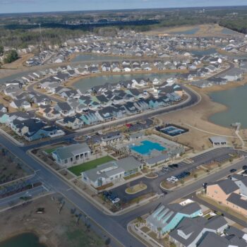 Aerial view: suburb with houses, roads, pool, ponds.
