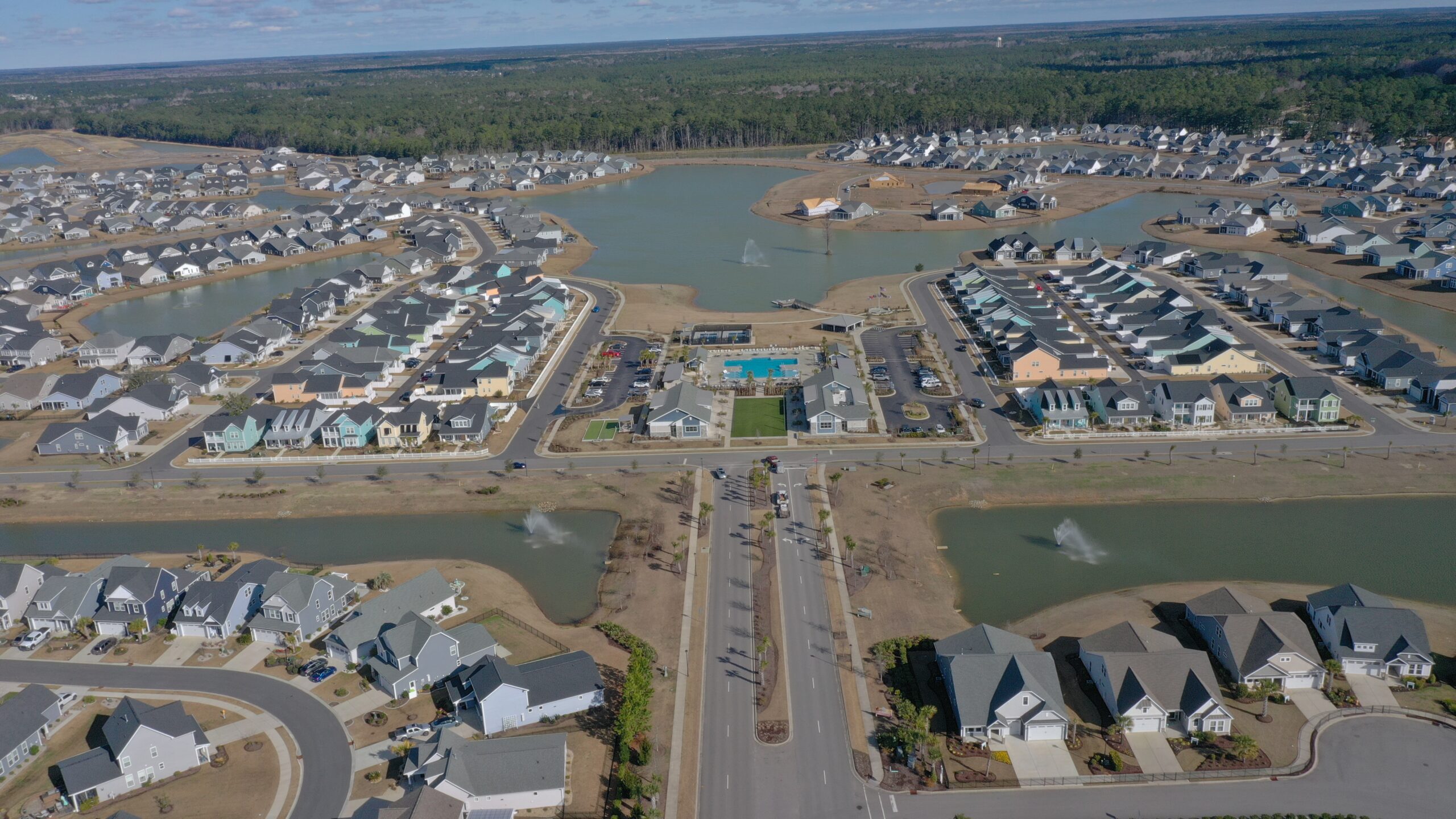 Aerial view: suburb with homes, ponds, fountains, pool area.
