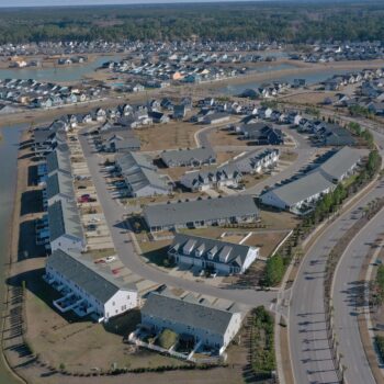Aerial view of suburb: houses, curved streets, canals, greenery.