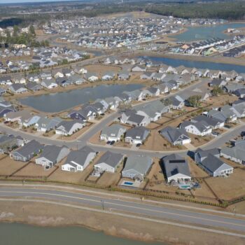 Aerial view of suburban homes, curved streets, ponds, green spaces.