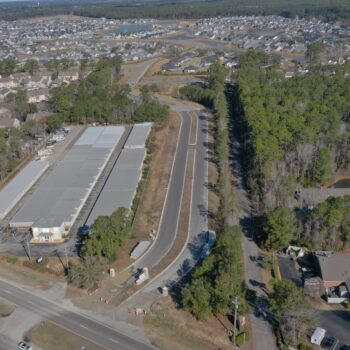Aerial view of divided road through buildings and trees.