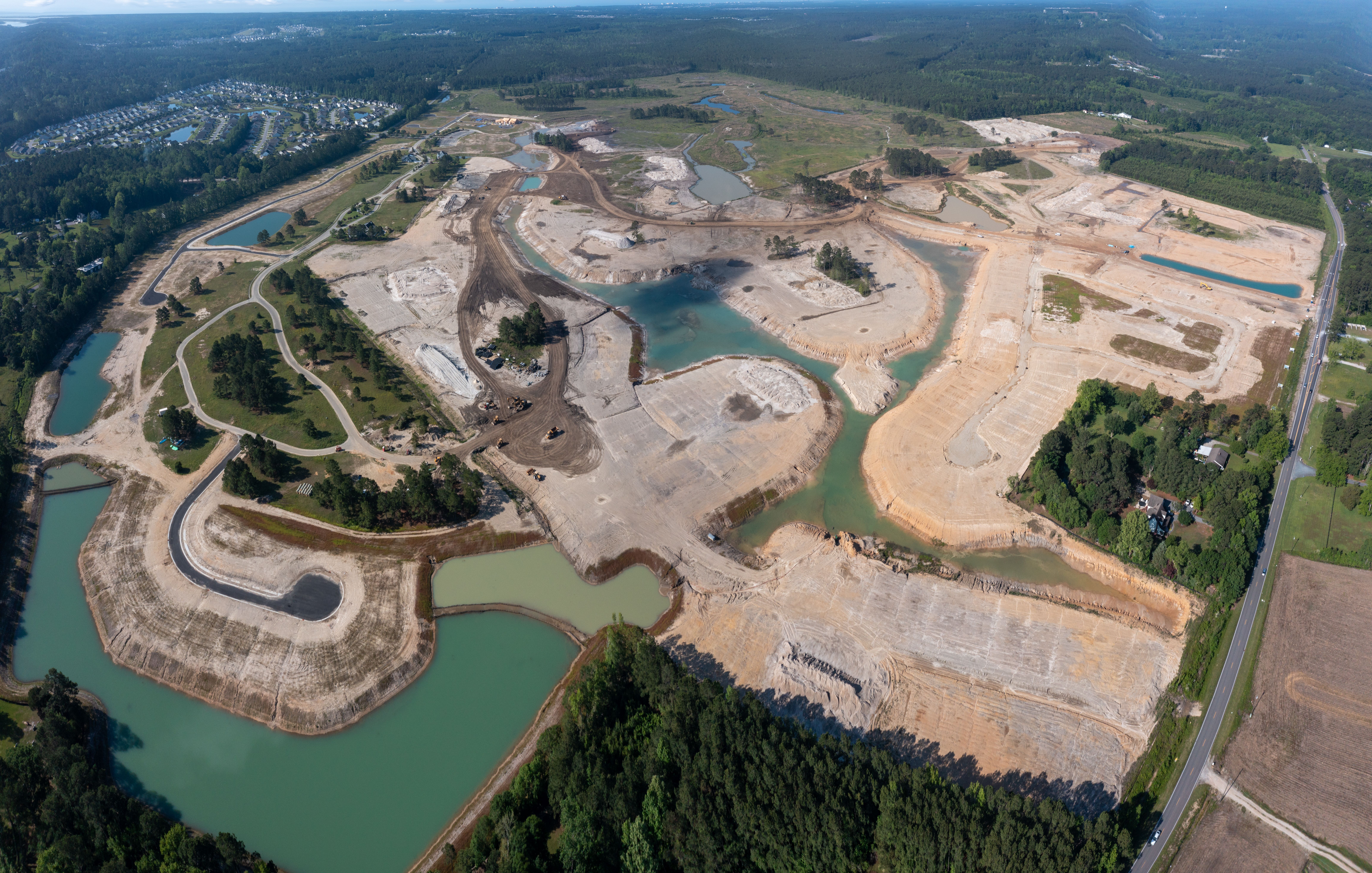 Aerial view: large construction site with roads, ponds, and trees.