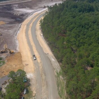Aerial view of a road between forest and construction site.