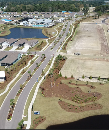 Aerial view: finished homes, landscaping, ponds, and construction nearby.