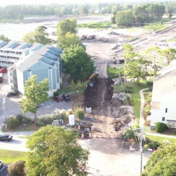 Aerial view: large trench between homes and sports facility.