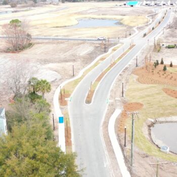 Aerial view: developing neighborhood with roads, plots, ponds, equipment.