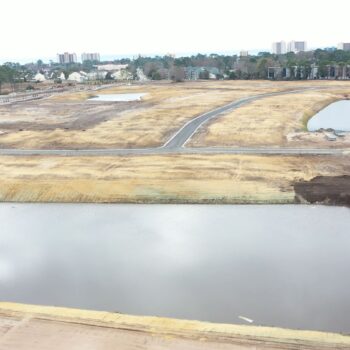 Aerial view: cleared land, buildings, roads, ponds, trees nearby.