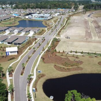 Aerial view of suburb: finished homes, roads, ponds, construction.