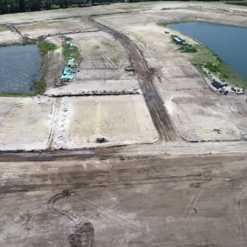Aerial view: construction site with ponds, dirt roads, vehicles.