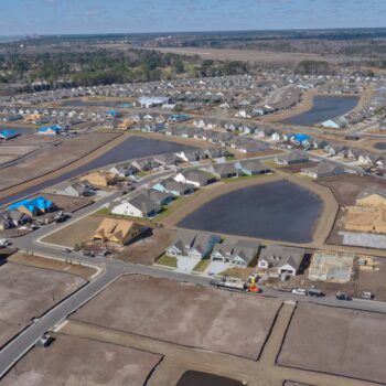 Aerial view: suburban homes, roads, and ponds under construction.