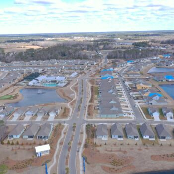 Aerial view of suburban homes, streets, lakes, and construction.
