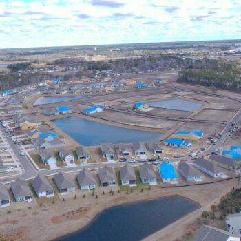 Aerial view: houses with blue tarps and ponds nearby.