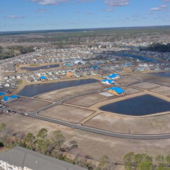 Aerial view of suburban homes under construction with blue roofs.