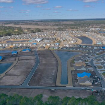 Aerial view of developing suburb with houses, roads, and ponds.