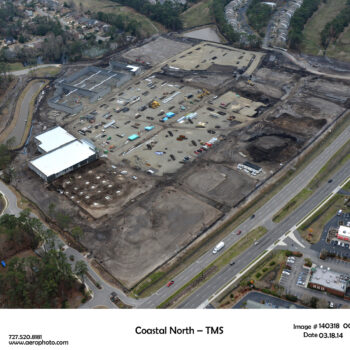 Aerial view of construction site amid cleared land and houses.