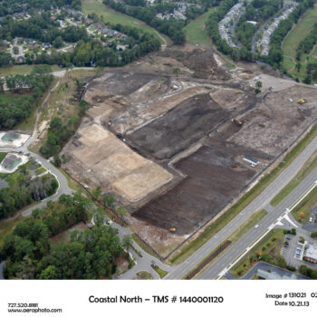 Aerial view of cleared construction site with nearby roads, homes.