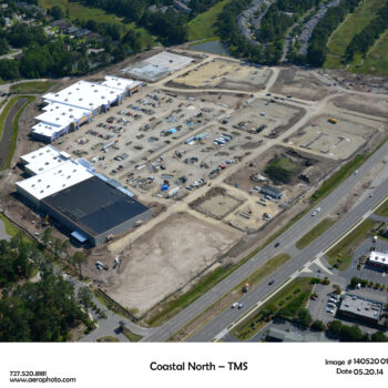 Aerial view of construction site with buildings, roads, and homes.