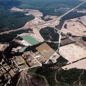Aerial view of farmland, reservoir, homes, roads, and forests.