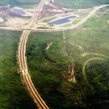 Aerial view: highway, interchange, forest, and two ponds.
