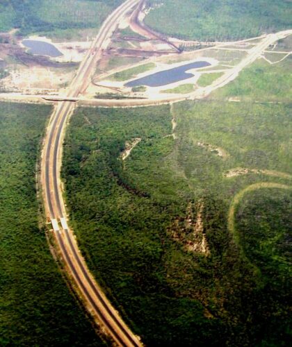 Aerial view: highway, interchange, forest, and two ponds.