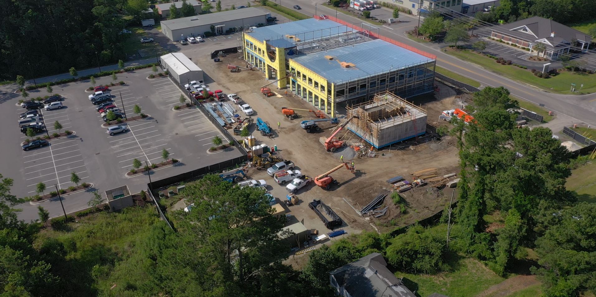 Aerial view: construction site, half-built building, vehicles, parking lot.