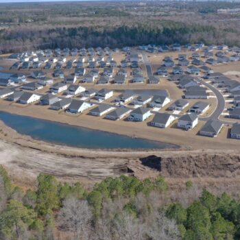 Aerial view of new suburban homes amid trees and ponds.