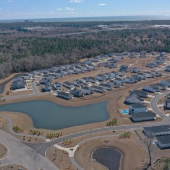 Aerial view of suburban houses, ponds, roads, and trees.