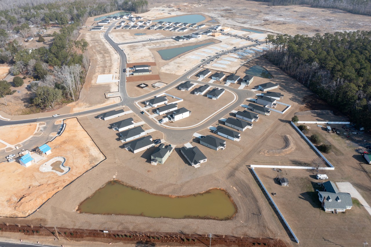 Aerial view: suburban homes, roads, ponds, some under construction.