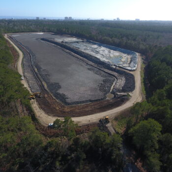 Aerial view: large construction site in forest, machinery visible.